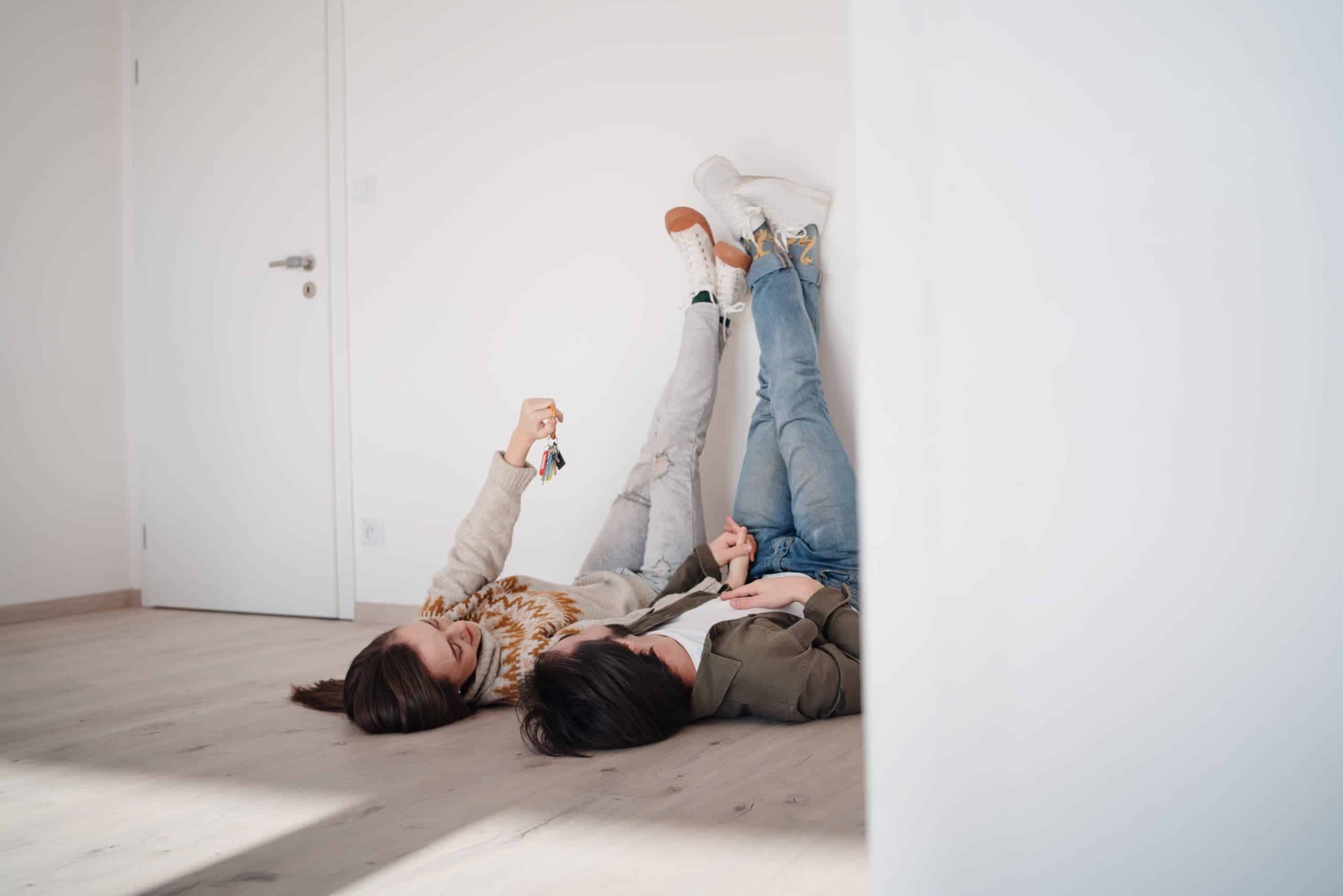 A young couple with keyslying on floor and moving in new flat, new home and relocation concept.